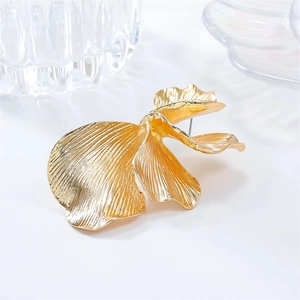 Close-up of golden ginkgo leaf earrings with irregular metal texture and polished finish