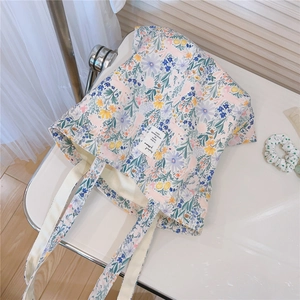 Detail of floral canvas tote bag featuring botanical prints on a modern white chair