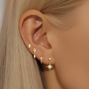 Detail of four-piece gold S925 silver earring set with star charms and zircons on model