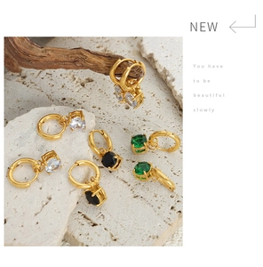 Dettaglio di orecchini vintage in oro con pietre di zircone in tre colori su pietra