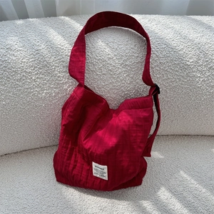 Detail of red pleated canvas tote bag showing vertical texture and white woven brand label