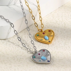 Détail du pendentif cœur avec opale centrale et strass colorés sur une chaîne à maillons