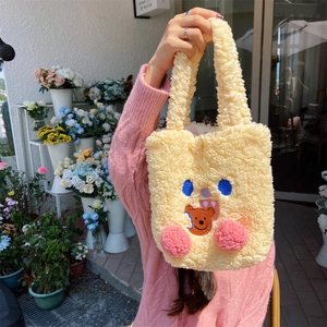 Detail of yellow plush tote bag with cute bear embroidery and 3D blush pom-poms