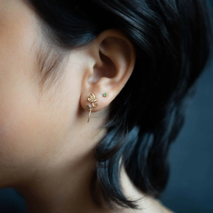 Classic gold rose stud earrings with green zircon accent on female model side profile