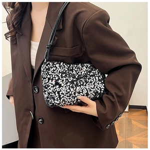 Detail of a chic black sequined baguette bag with silver accents on a brown blazer outfit