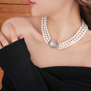 Detail of multi-layer pearl necklace featuring a floral silver clasp with diamond accents