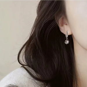 Close-up of S925 sterling silver hoop earring with sun pendant on a model's ear