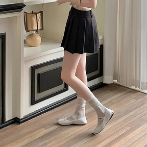 Detail weißer, hohler Spitzensocken kombiniert mit schwarzem Faltenrock und Ballettschuhen
