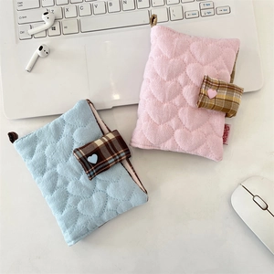 Close-up of pink and blue heart quilted fabric notebook covers on a white desk setup
