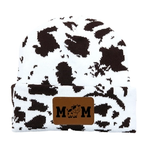 Detail of knitted cow print beanie with brown leather MOM patch and cow icon