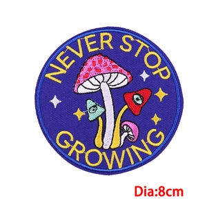 Detailed view of 8cm mushroom embroidery patch with Never Stop Growing slogan