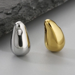 Macro shot of 12x6mm teardrop pendants in gold and silver steel on a textured rock