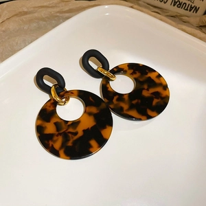 Detailed view of leopard print resin hoop earrings on a minimalist white ceramic tray