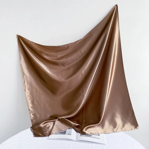 Detail view of glossy brown satin silk square scarf with soft drape and smooth texture