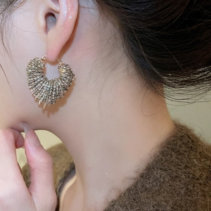 Close-up of heart-shaped beaded earrings with grey crystals worn on the ear