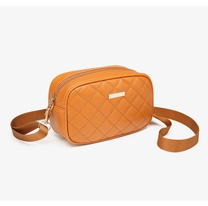 Detail of orange-brown quilted cross-body bag with golden zipper and adjustable strap