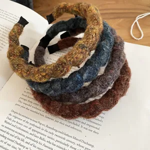 Knitted wavy headbands in multiple colors displayed on an art book with pearls