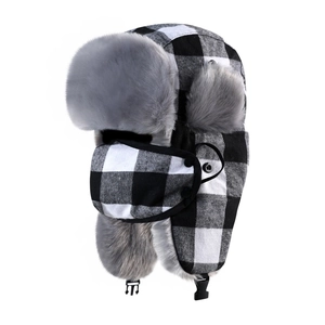 Detail of winter trapper hat with black and white plaid pattern and grey faux fur lining