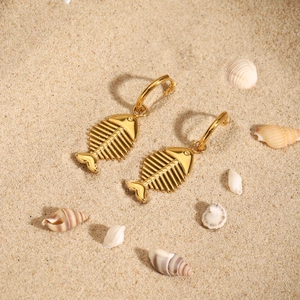 18K gold plated fishbone pendant earrings displayed on a sandy beach with seashells