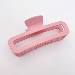 Detail of a pink matte square hair claw clip with a hollow design on white fabric
