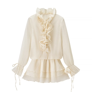 Detail of ruffle collar, 3D floral accent and tiered hem on creamy white chiffon top