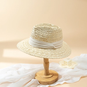 Elegant beige woven straw fedora sun hat with decorative ribbon on a minimalist stand
