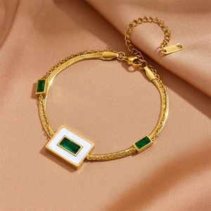 Detailed shot of golden stainless steel bracelet with green zircon and white enamel
