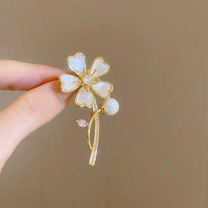Vue détaillée d'une broche fleur plaquée or avec pétales blancs et une perle