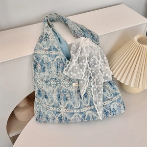 Detailed view of blue canvas tote bag with intricate white embroidery and lace bow