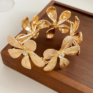 Detailsicht eines luxuriösen Goldblumenarmbands mit funkelnden Kristallsteinen auf Blüten