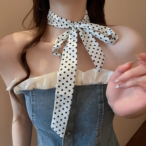 Close-up of black and white polka dot silk scarf tied as a bow with denim top