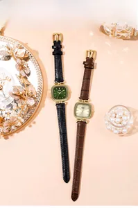 Detail of vintage square quartz watches with leather straps and gold cases in warm setting