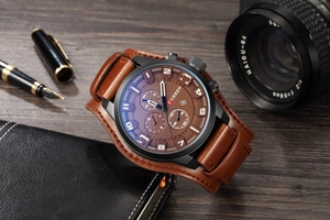 Brown leather strap watch with black dial and calendar on a rustic wooden desk