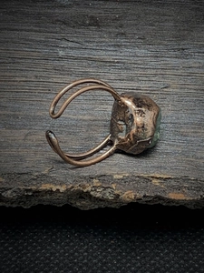 Detail view of a vintage adjustable ring with green raw stone on rustic wood