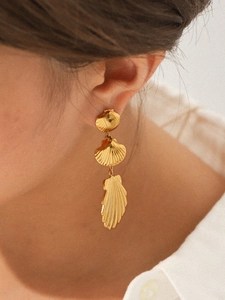 Close-up of triple-layered 18K gold stainless steel shell tassel earrings on model