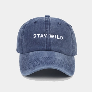 Detail of washed blue baseball cap featuring white STAY WILD embroidery and cotton texture