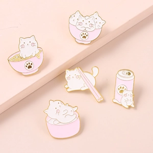 Gros plan sur cinq épingles en émail de chats mignons aux motifs de dessins animés roses