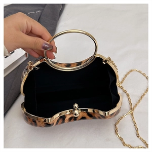Detail view of leopard print evening clutch bag with gold handle and chain on white fabric