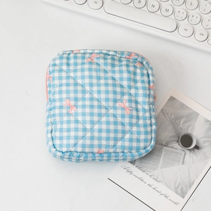 Detail view of a quilted blue gingham toiletry bag with pink bow prints and zipper