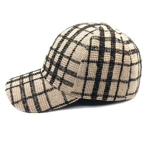 Dettaglio del berretto da baseball in tweed beige con motivo a quadri nero e oro