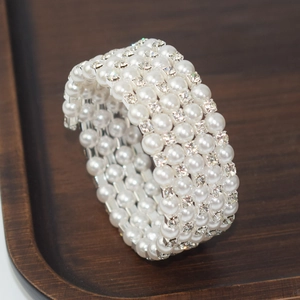 Macro shot of 4-layer pearl bracelet with square rhinestones on a wooden tray