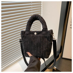 Detailed macro view of black corduroy bucket bag texture with top handle and white button