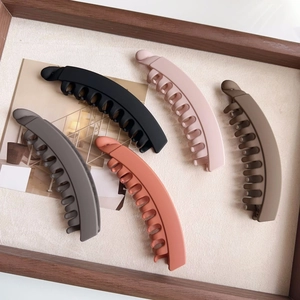 Flat lay of five matte finish banana hair clips in black grey coral pink and taupe colors