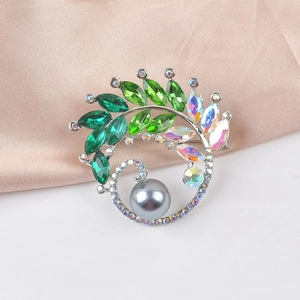 Detailed shot of green crystal leaf brooch with grey pearl on pink silk background
