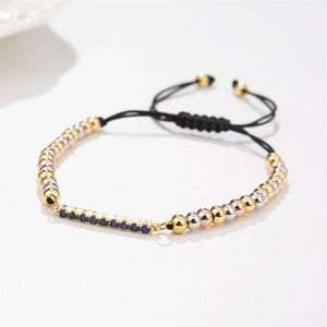 Macro view of blue zircon bar on black woven cord bracelet with adjustable gold slider