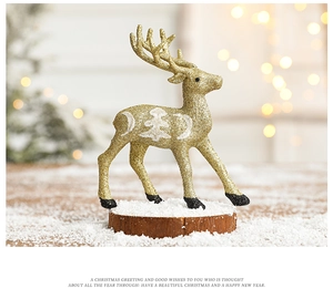 Macro detail of a gold glitter Christmas reindeer figurine on a wooden base with faux snow