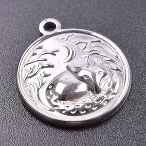 Detail of silver stainless steel round charm featuring embossed moon and fox carving