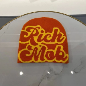 Detail of orange knitted beanie featuring bold red Rich Mob lettering with yellow borders