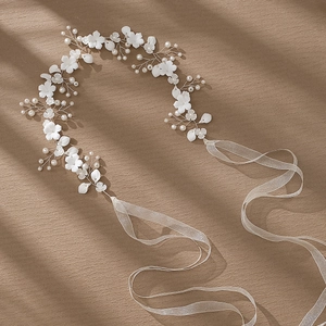 Detail of bridal floral headband with white ceramic flowers, pearls and mesh ribbon