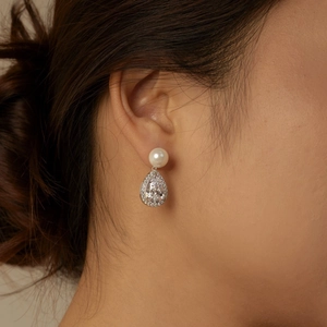 Detailed view of silver drop earrings with white pearl and teardrop zircon on a model